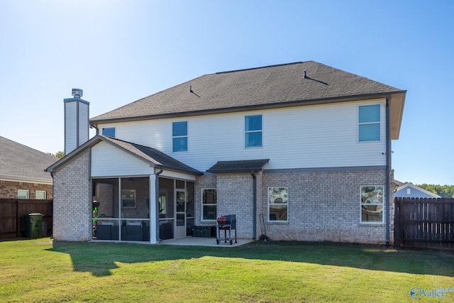 rear view of property with a lawn, a patio area, and a sunroom