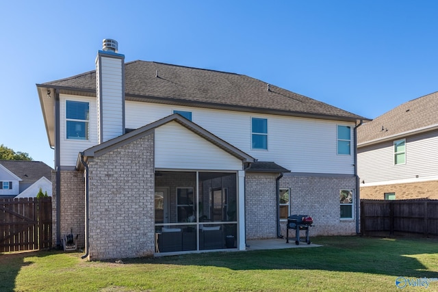 back of property with a patio, a sunroom, and a lawn