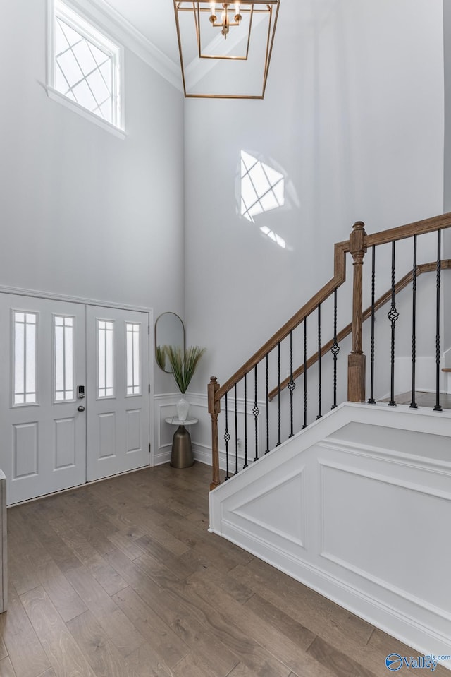 entrance foyer with hardwood / wood-style flooring, ornamental molding, a wealth of natural light, and an inviting chandelier