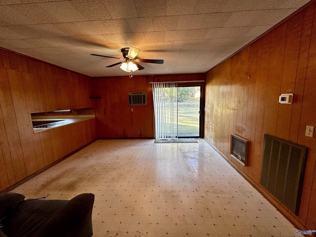 unfurnished living room with an AC wall unit, wood walls, and ceiling fan