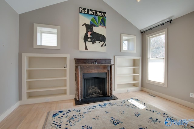 unfurnished living room featuring built in shelves, baseboards, vaulted ceiling, a fireplace, and wood finished floors