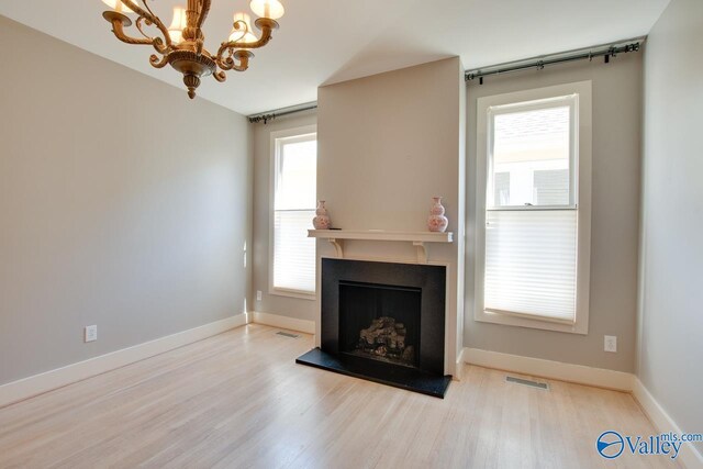 unfurnished living room featuring visible vents, a healthy amount of sunlight, a fireplace with raised hearth, and wood finished floors