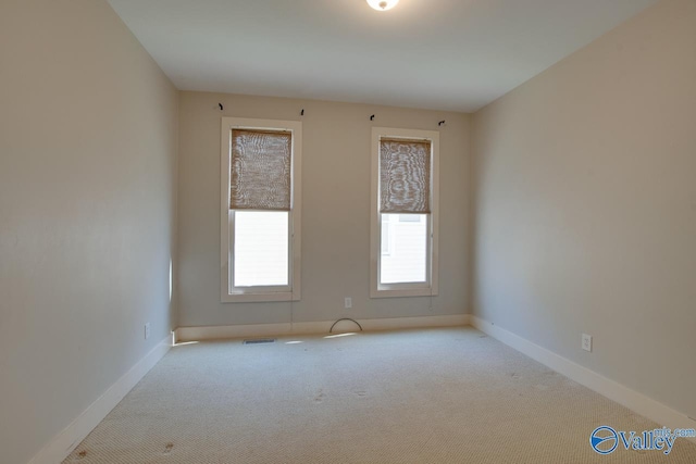 carpeted spare room featuring visible vents and baseboards