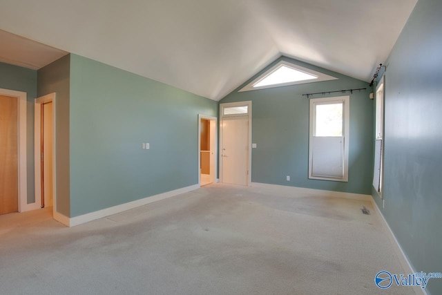 spare room with light colored carpet, baseboards, lofted ceiling, and a barn door