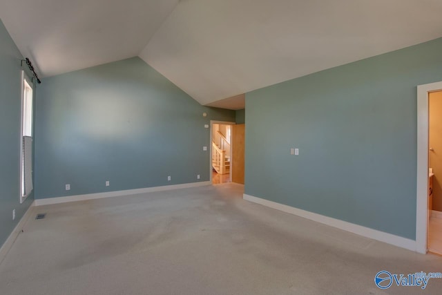 carpeted spare room with stairway, lofted ceiling, baseboards, and visible vents