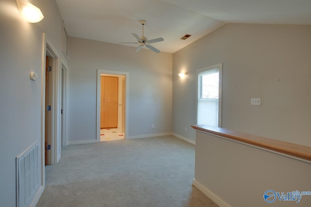 unfurnished room featuring visible vents, baseboards, light colored carpet, and vaulted ceiling