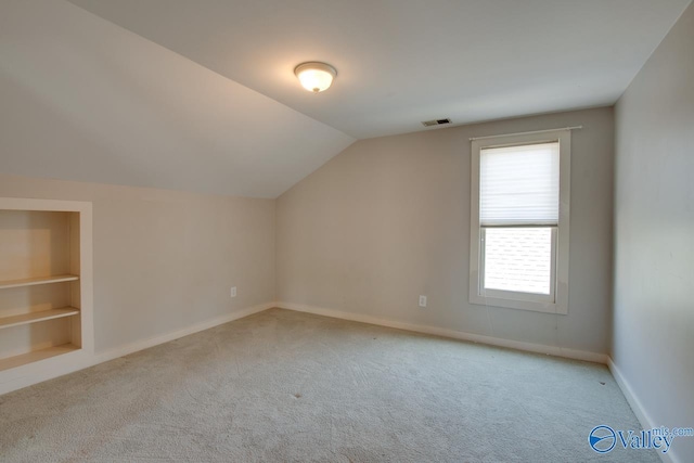 additional living space with baseboards, built in shelves, lofted ceiling, and carpet flooring