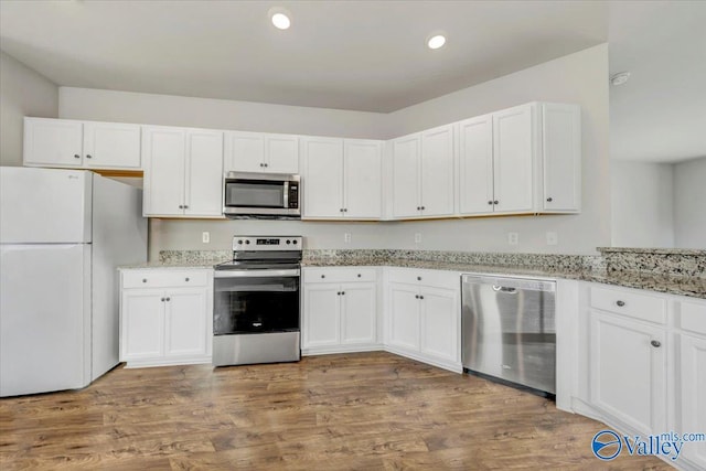 kitchen featuring light stone counters, white cabinets, stainless steel appliances, and recessed lighting