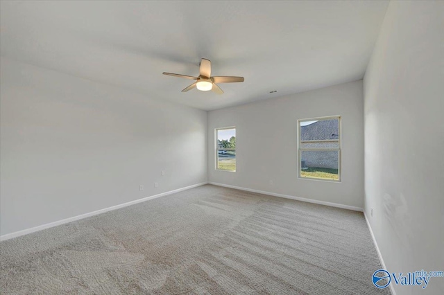 carpeted spare room featuring a ceiling fan and baseboards