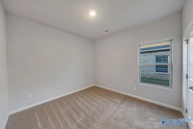carpeted spare room featuring baseboards and visible vents
