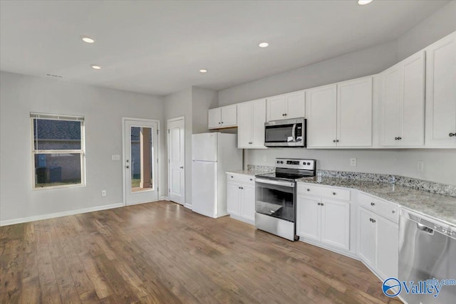 kitchen featuring white cabinetry, stainless steel appliances, light stone countertops, and hardwood / wood-style flooring