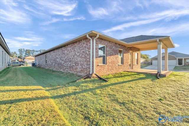 view of side of property with brick siding and a yard