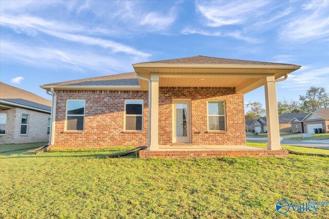 back of property with brick siding and a yard