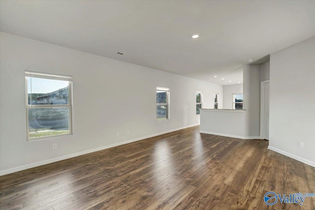 unfurnished living room with recessed lighting, baseboards, and dark wood-style flooring