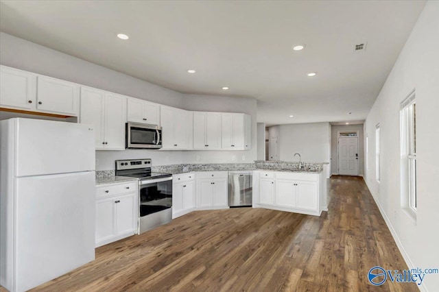 kitchen featuring recessed lighting, dark wood finished floors, stainless steel appliances, a peninsula, and white cabinetry