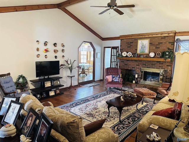 living room featuring baseboards, a ceiling fan, lofted ceiling with beams, wood finished floors, and a brick fireplace