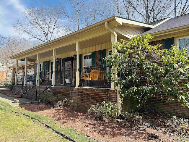 exterior space with a porch, crawl space, and brick siding