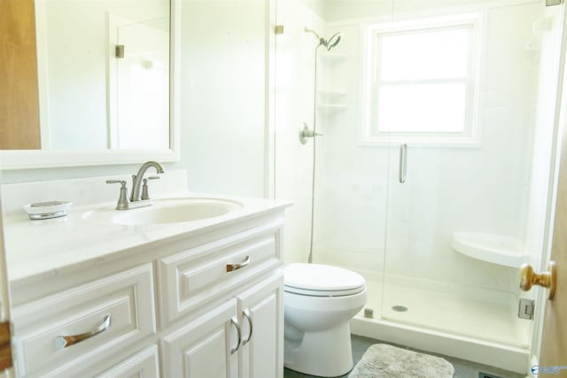 bathroom with toilet, vanity, and a shower with shower door