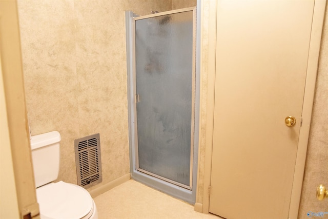 bathroom with toilet and a shower with door