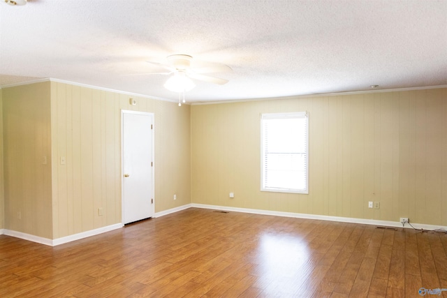 unfurnished room with wood walls, ceiling fan, hardwood / wood-style flooring, and ornamental molding