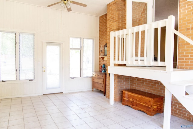 interior space with a towering ceiling, ceiling fan, and brick wall