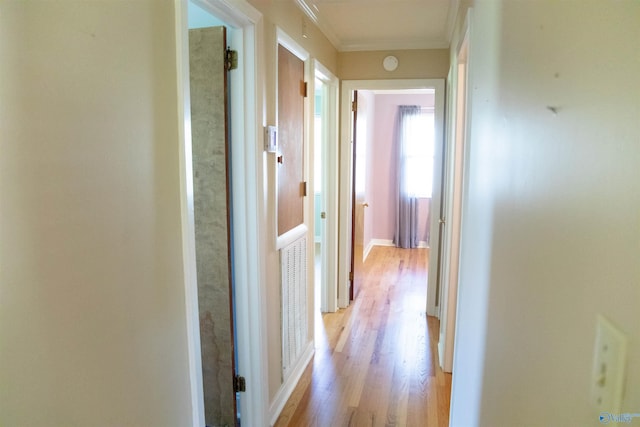 corridor with ornamental molding and light wood-type flooring