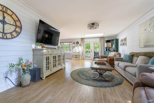 living room with wooden walls, light wood-type flooring, and crown molding