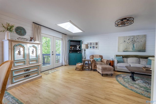 living area with wooden walls, wood finished floors, a skylight, and french doors