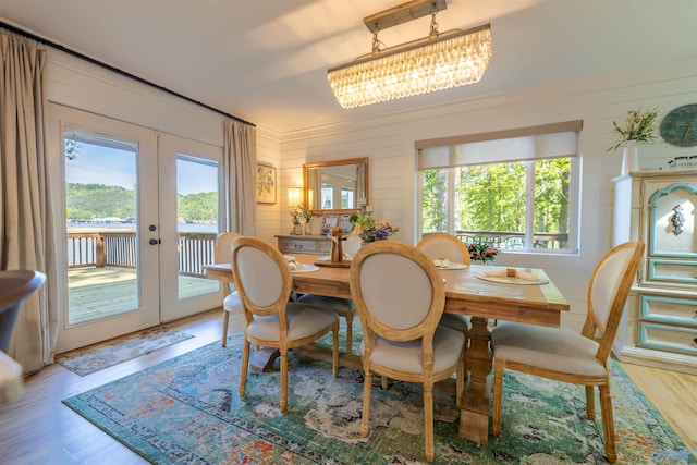 dining space with french doors, wood finished floors, and an inviting chandelier