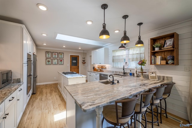 kitchen featuring white cabinets, ornamental molding, light stone countertops, and stainless steel appliances