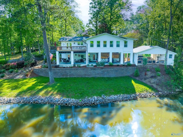 back of house featuring a patio area, a deck with water view, a yard, and a detached carport