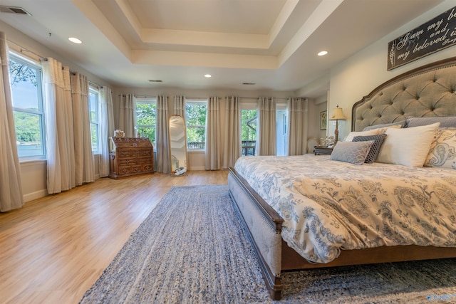 bedroom with recessed lighting, a raised ceiling, visible vents, light wood-style floors, and baseboards