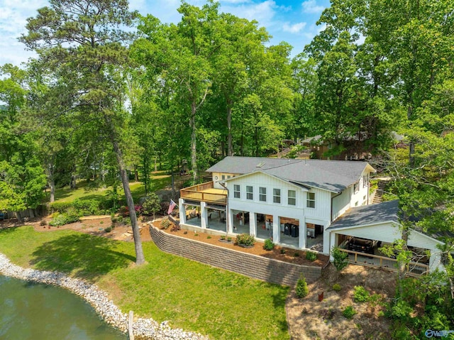 exterior space featuring a lawn, a shingled roof, and a deck with water view