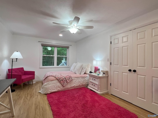 bedroom with light wood-style flooring, a closet, a ceiling fan, and baseboards