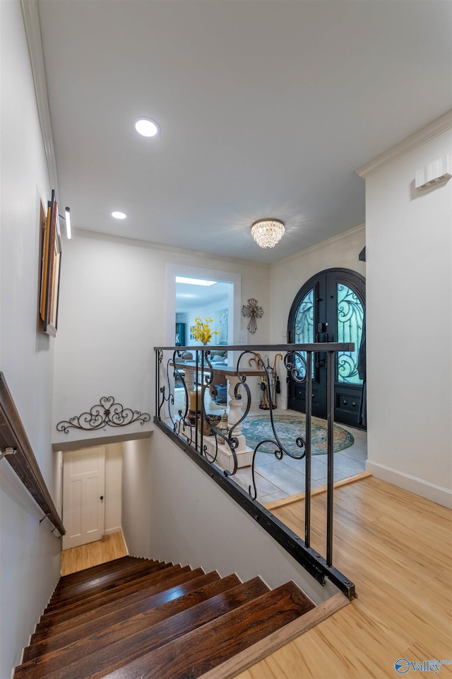 staircase with recessed lighting, wood finished floors, baseboards, and ornamental molding
