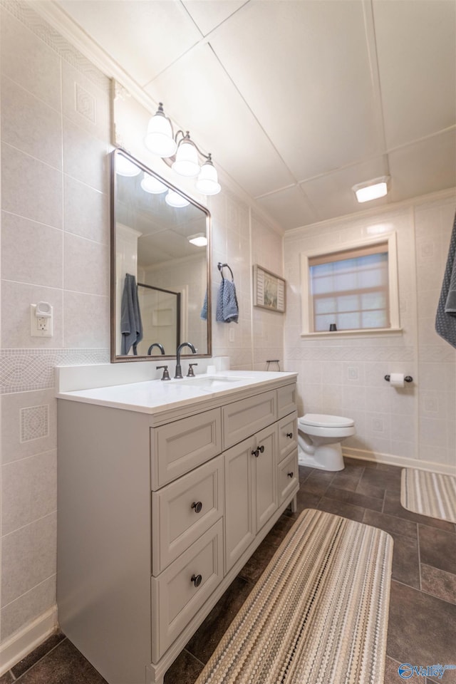 full bath with toilet, vanity, a shower, and tile walls