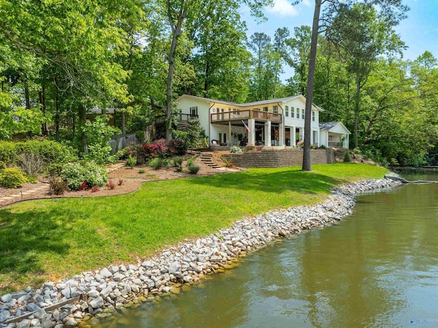 rear view of house with a yard, a deck with water view, and stairs