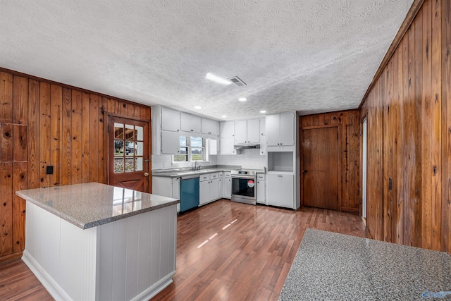 kitchen featuring appliances with stainless steel finishes, a textured ceiling, wooden walls, dark hardwood / wood-style floors, and white cabinetry