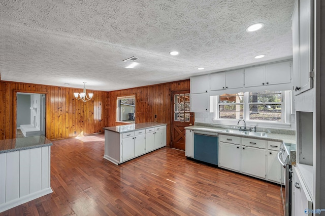 kitchen with dark hardwood / wood-style flooring, a textured ceiling, sink, white cabinetry, and wood walls