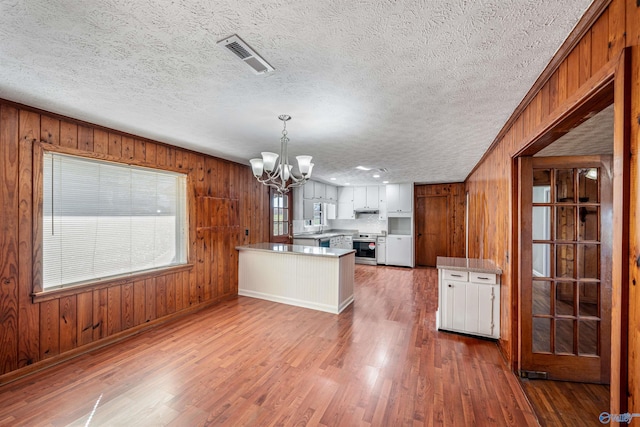 kitchen featuring stainless steel range with electric cooktop, white cabinets, a notable chandelier, dark hardwood / wood-style flooring, and kitchen peninsula