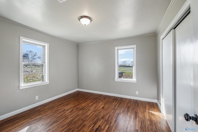 empty room with a healthy amount of sunlight, dark hardwood / wood-style flooring, and crown molding