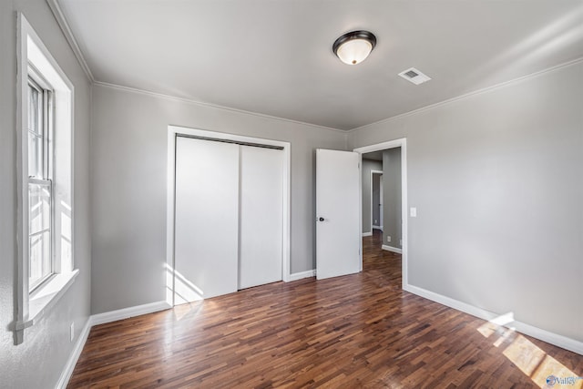 unfurnished bedroom with crown molding, a closet, and dark wood-type flooring