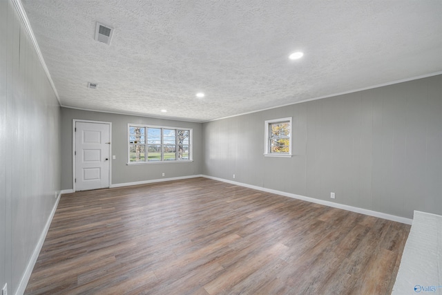 empty room with hardwood / wood-style floors, a textured ceiling, and crown molding