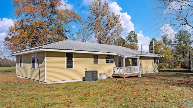 rear view of property featuring central AC unit, a deck, and a lawn