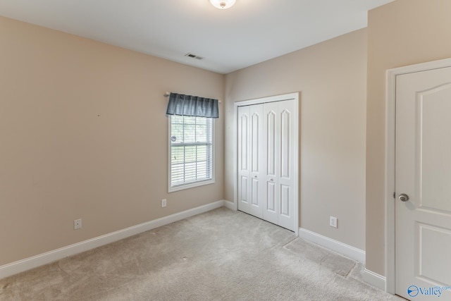 unfurnished bedroom featuring light carpet and a closet