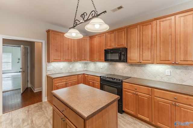 kitchen featuring pendant lighting, light wood-type flooring, a kitchen island, decorative backsplash, and black appliances