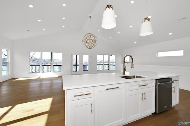 kitchen with decorative light fixtures, a kitchen island with sink, sink, and white cabinets