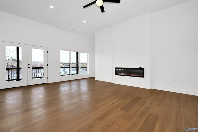 unfurnished living room featuring hardwood / wood-style flooring, plenty of natural light, a large fireplace, and french doors