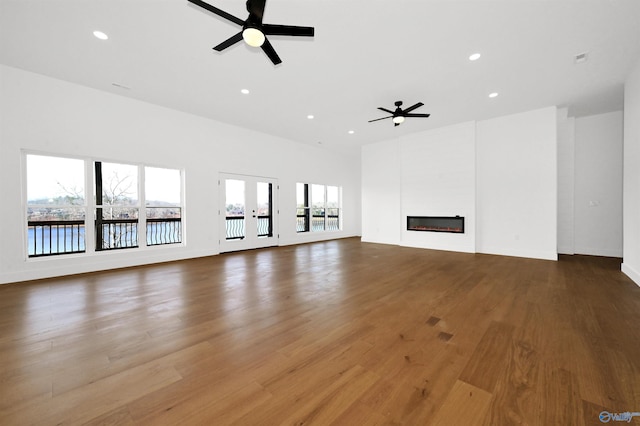 unfurnished living room with hardwood / wood-style flooring, ceiling fan, and french doors