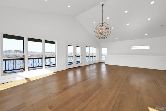 unfurnished living room with dark wood-type flooring, a chandelier, high vaulted ceiling, and french doors